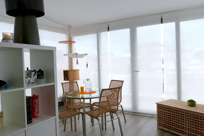 Bright dining corner with a glass table, wicker chairs and blinds after a brightness and colour correction